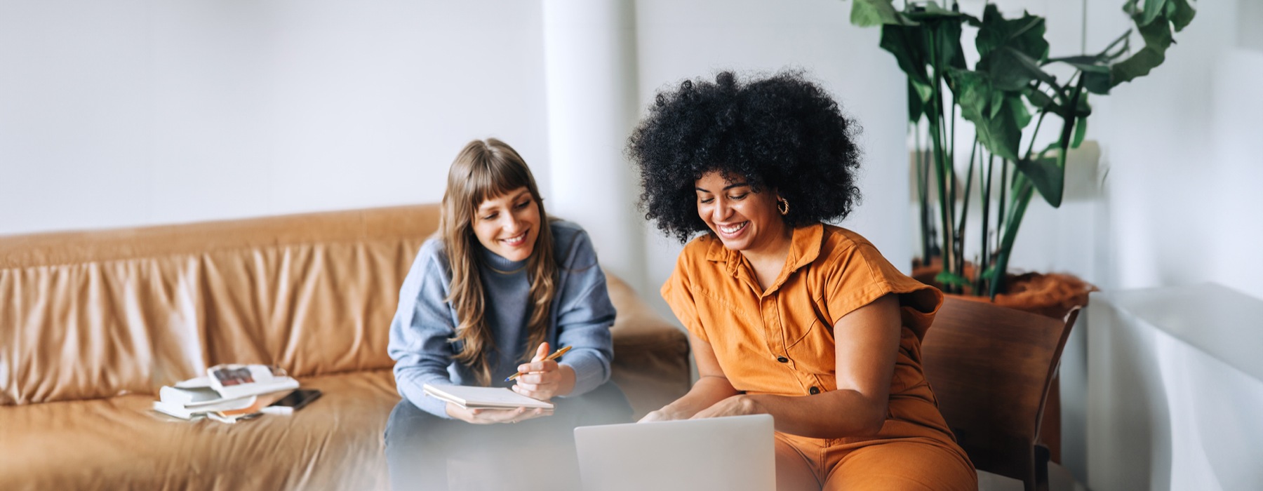 a couple of women sitting at a table looking at a laptop